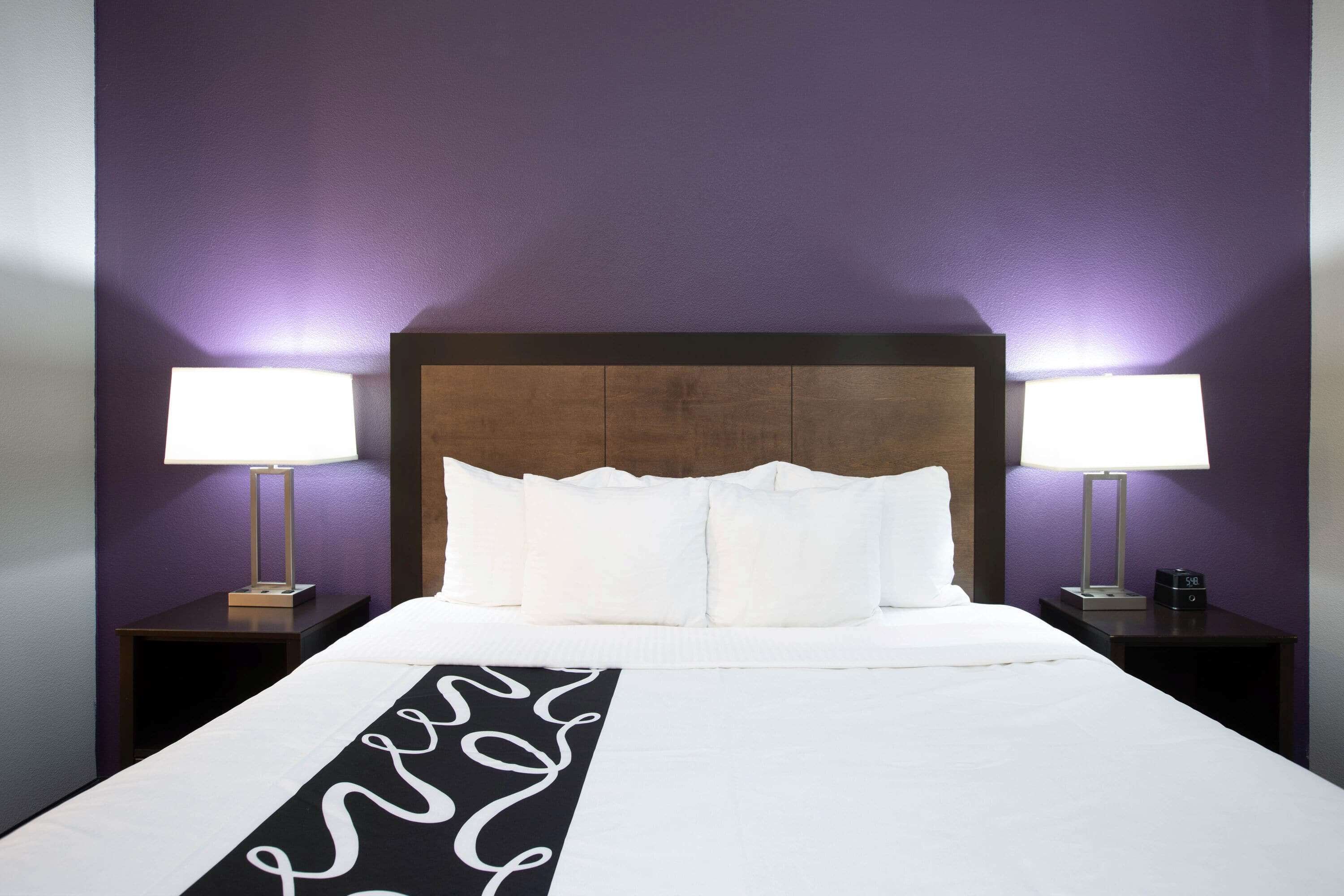 A hotel room with a large bed, two bedside tables, and a headboard.