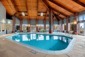 An indoor swimming pool with a wooden ceiling, brick walls, and a clear glass exit door. - La Quinta Inn by Wyndham Livermore (Livermore)