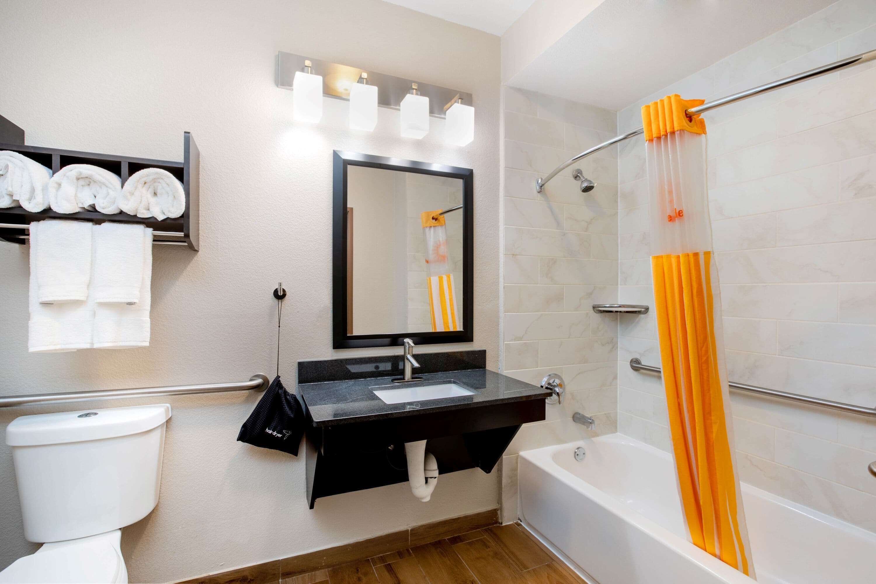 A bathroom with a toilet, sink, mirror, and bathtub.