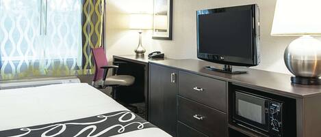 Hotelkamer met een bed, een bureau met een televisie, een lamp, een telefoon en een magnetron.