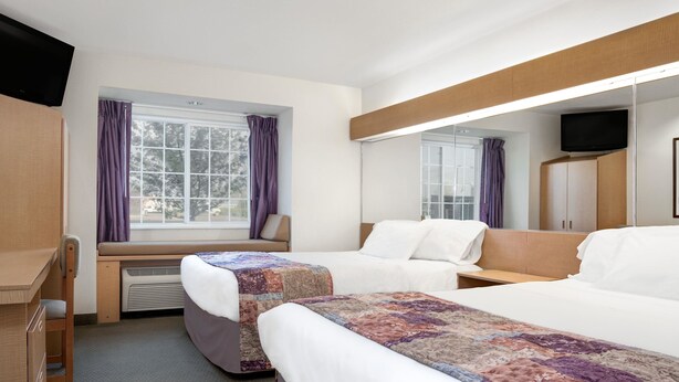 A hotel room with two beds, a desk, a chair, a window with curtains, a television, and a wardrobe. - Microtel Inn & Suites by Wyndham Mankato (Mankato)