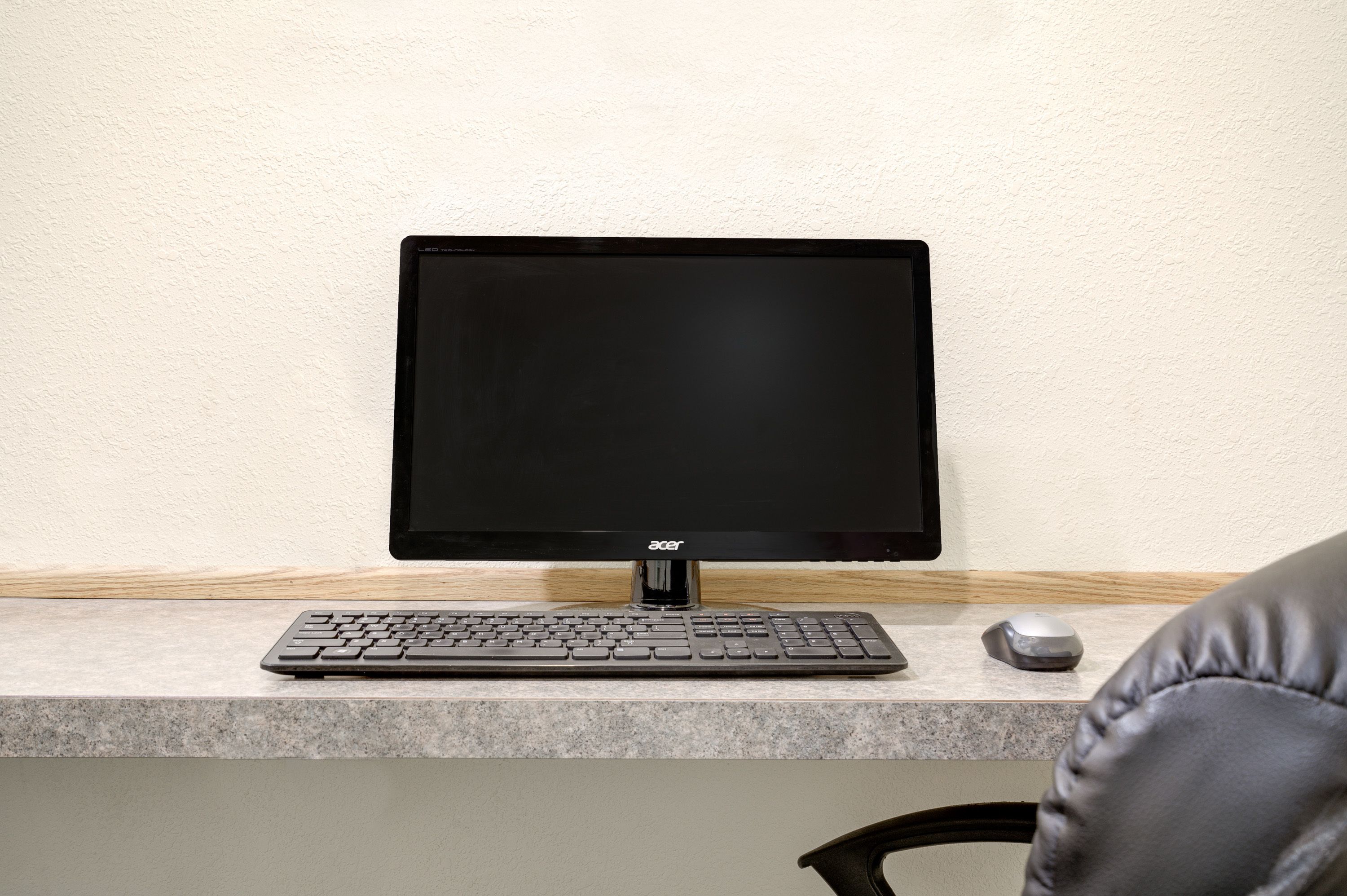 Un écran Acer noir est posé sur un bureau, avec un clavier et une souris à proximité.