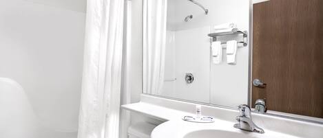 Un baño moderno con un lavamanos blanco, un espejo y una cortina de ducha.