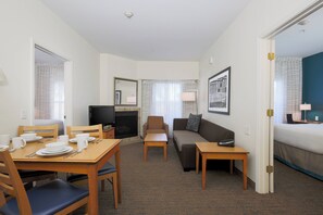 Une chambre d’hôtel comprenant un coin repas, un canapé, une télévision et une cheminée.