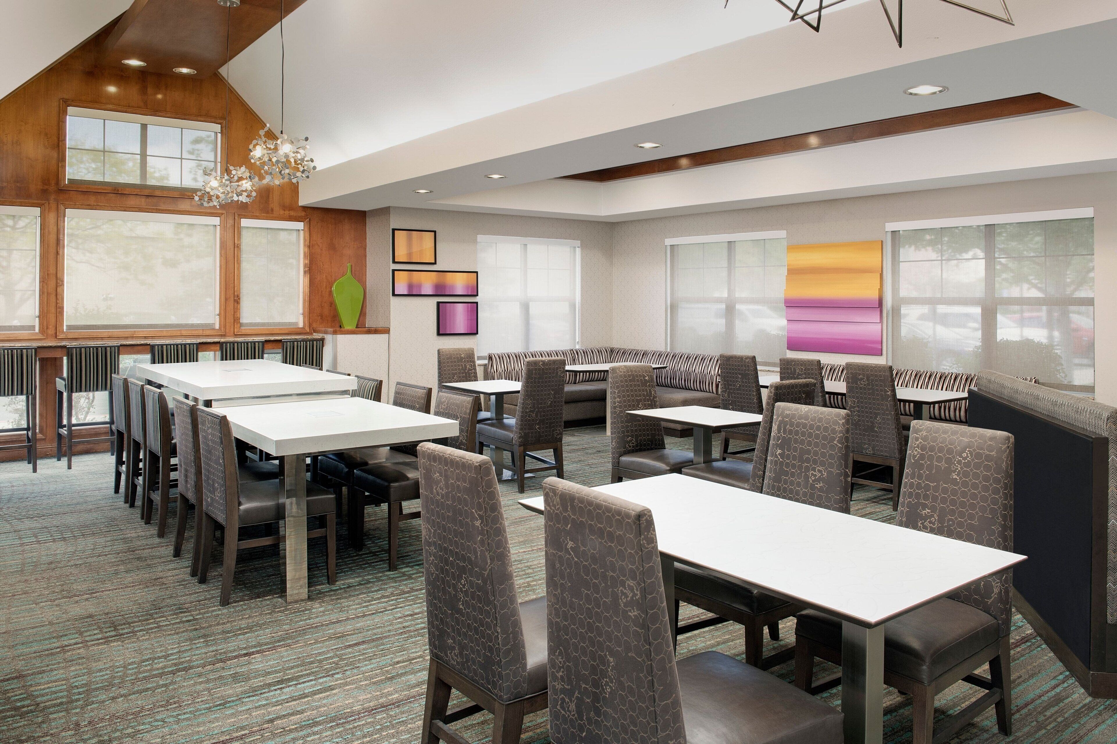 A modern dining area with high tables and cushioned booths, large windows, and contemporary decor.