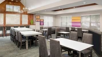 A modern dining area with high tables and cushioned booths, large windows, and contemporary decor.