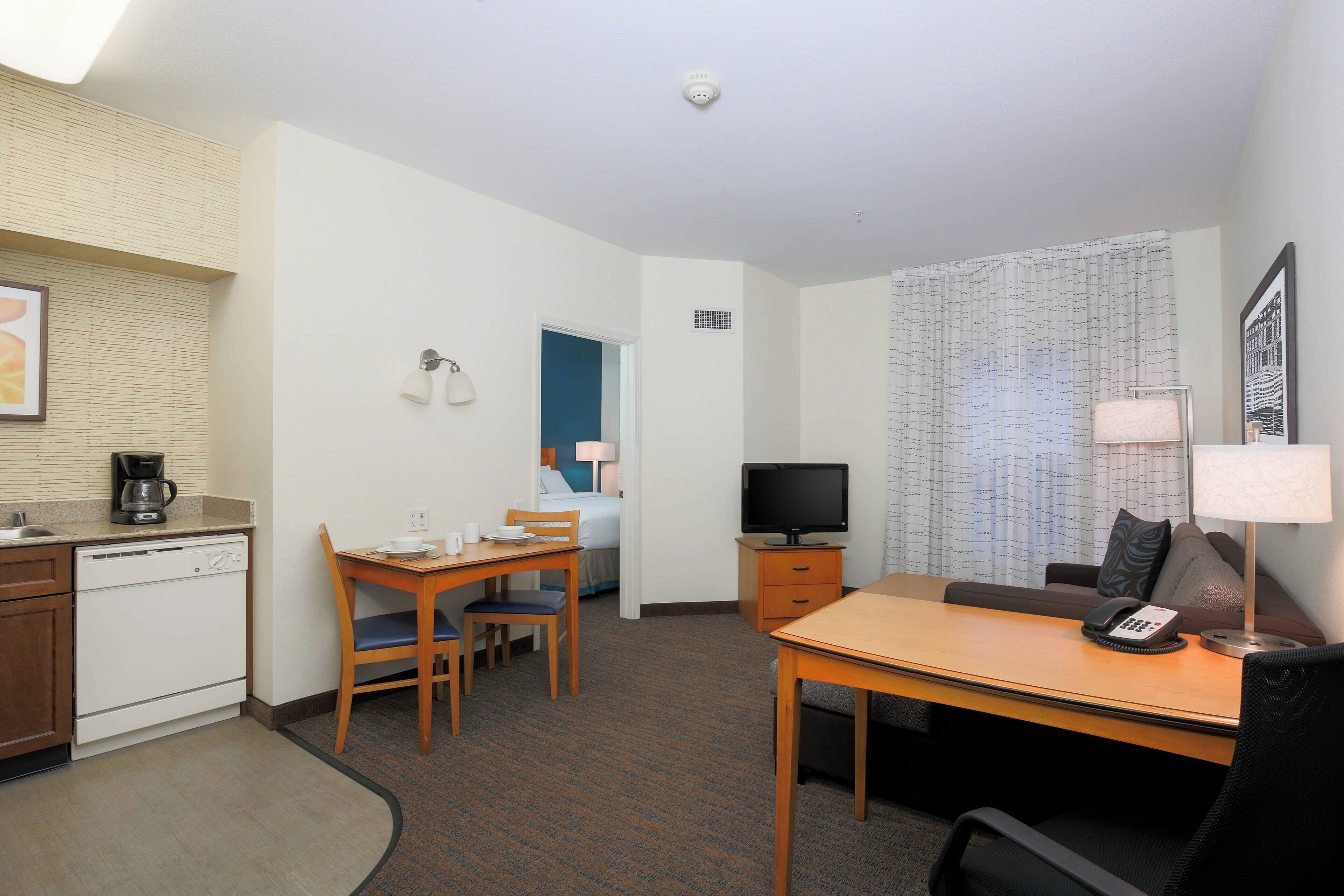 Une chambre d’hôtel équipée d’une kitchenette, d’un coin repas avec une table et des chaises, d’une télévision, d’un canapé et d’un lit.