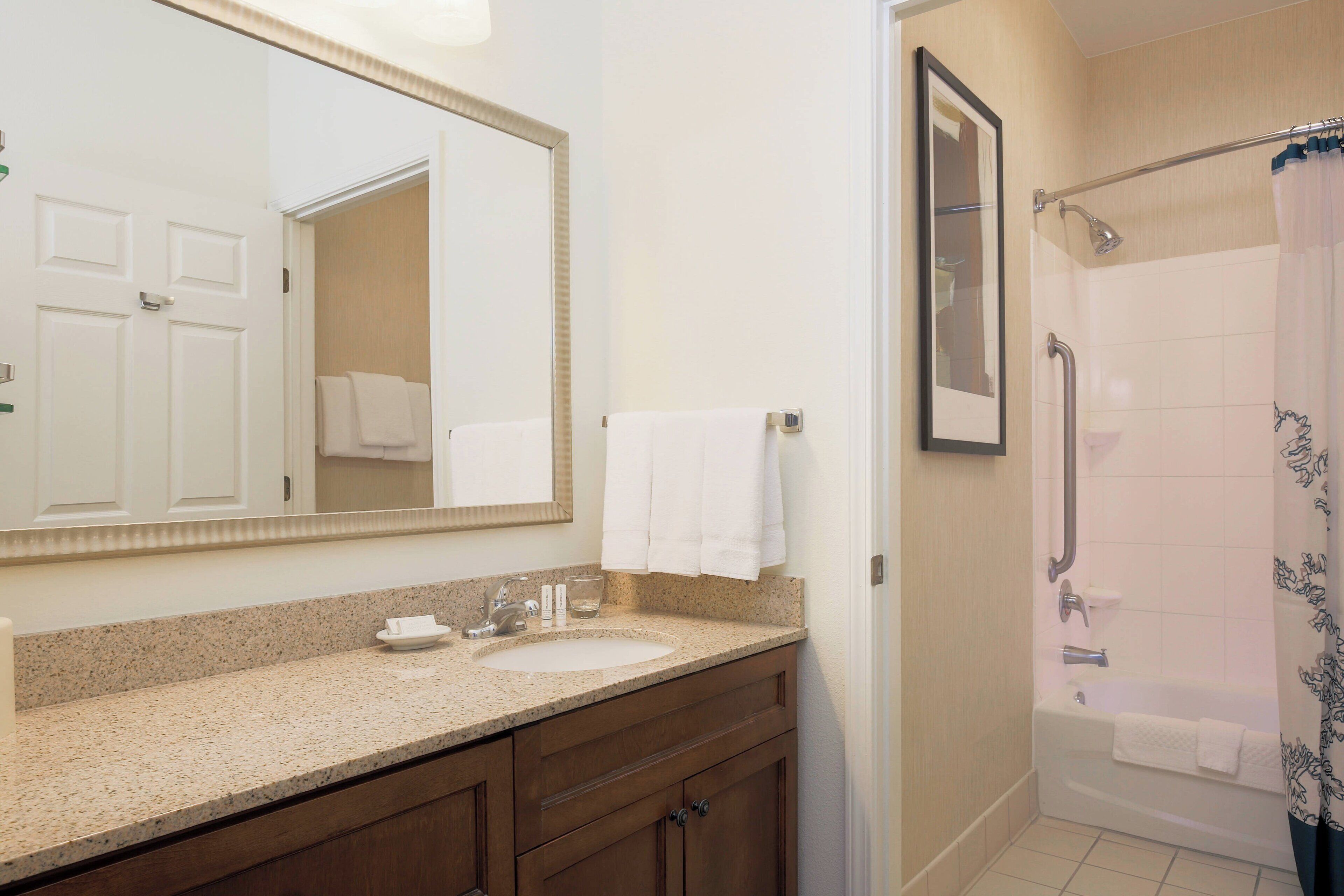 A bathroom with a sink, mirror, and shower area.