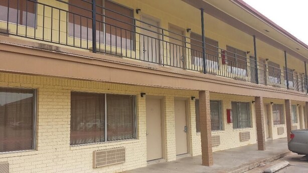A multi-story motel with a brick facade, multiple balconies, and a parking area. - Express Inn - Bay City (Bay City)