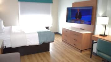 Ein Hotelzimmer mit Bett, Schreibtisch, Fernseher und Lampe.