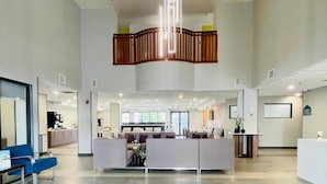 A spacious lobby with a central seating area, a reception desk, and a modern light fixture. - Wingate by Wyndham Vienna/Parkersburg/Marietta (Vienna)
