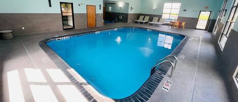 Une piscine intérieure à l’eau claire, dotée de couloirs délimités et d’un sol carrelé.
