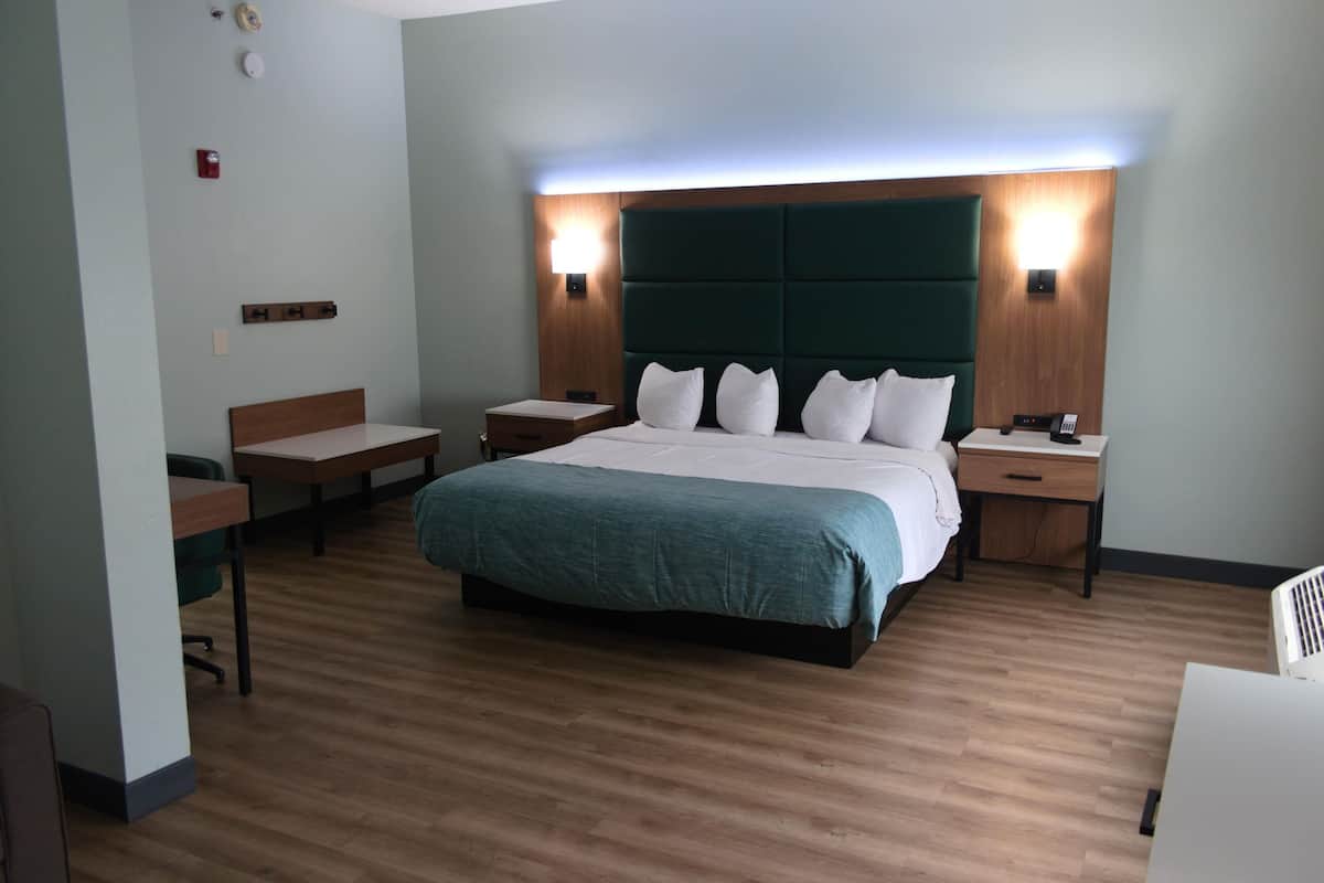 A hotel room with a large bed, two bedside tables, a desk, and a chair.