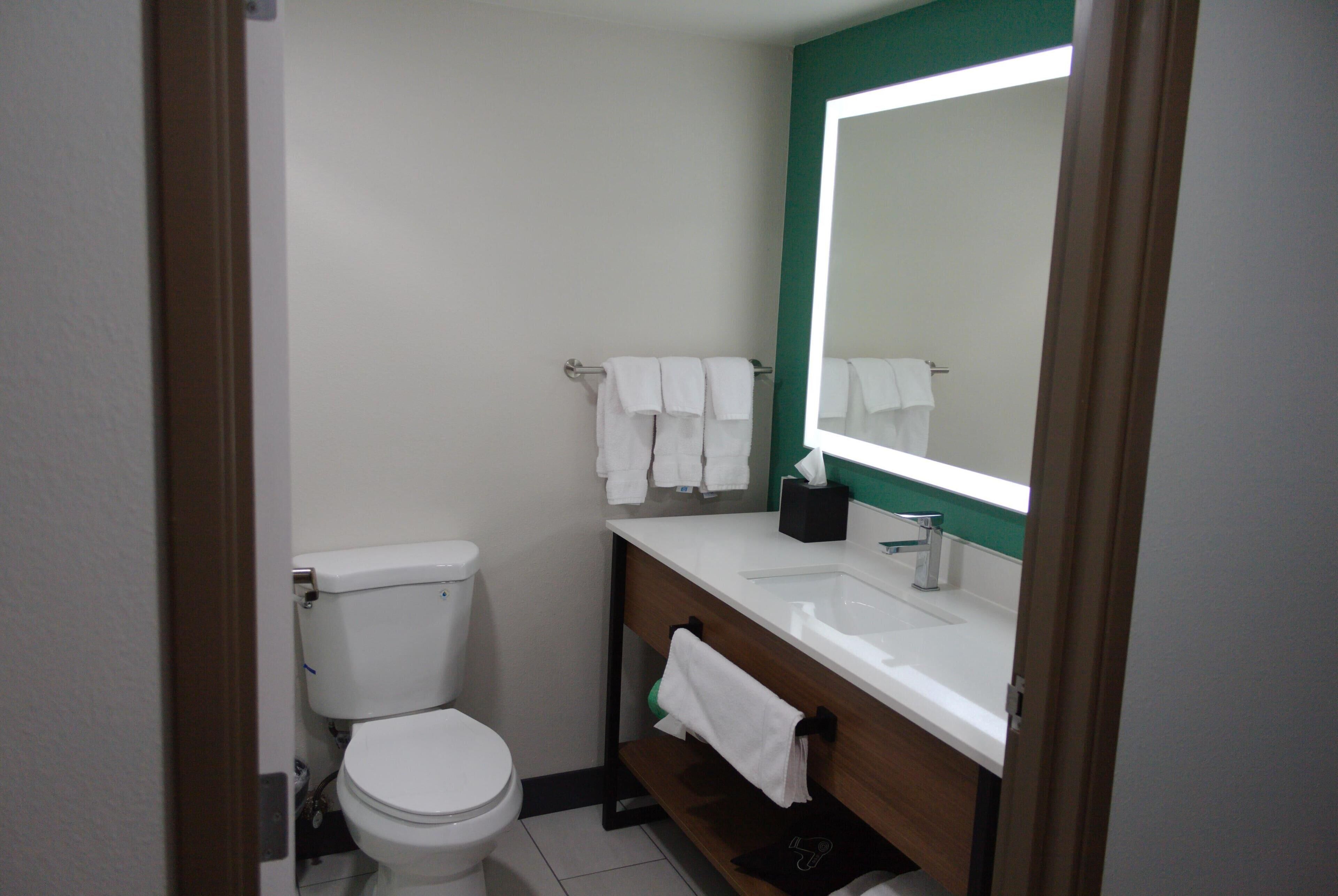 A small, clean bathroom with a white toilet, a sink, and a mirror.