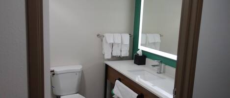 A small, clean bathroom with a white toilet, a sink, and a mirror.