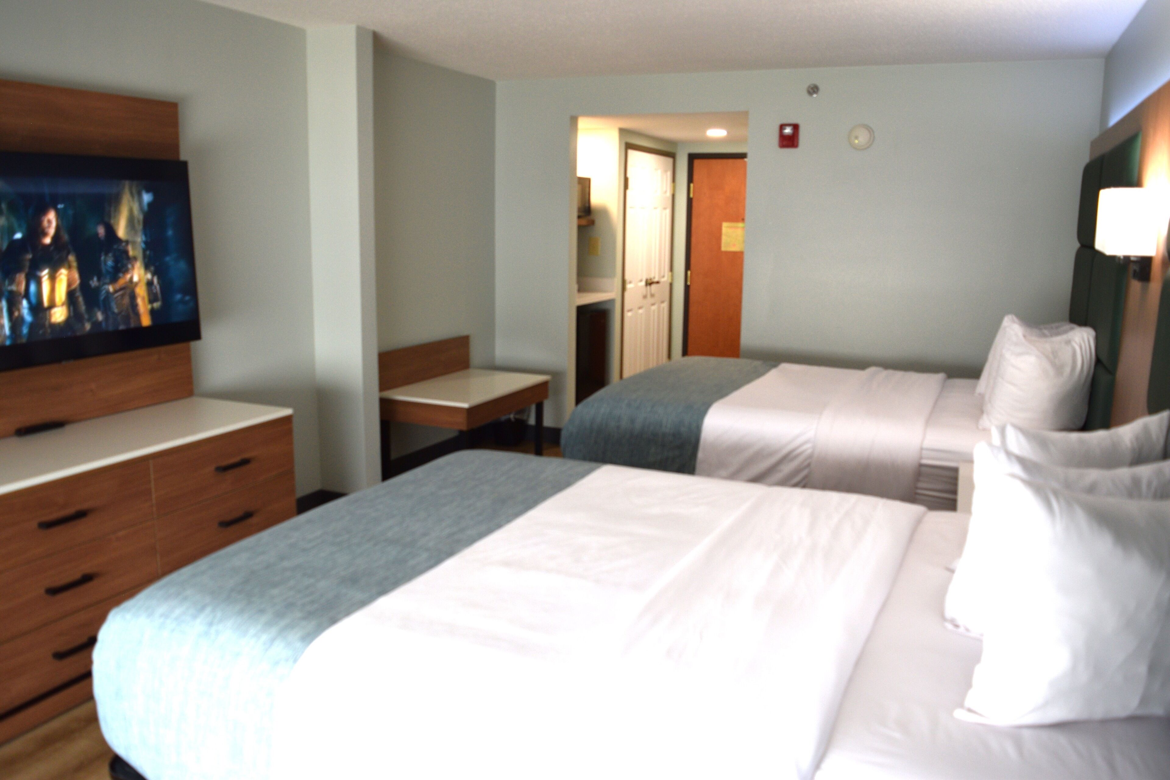 A hotel room with two beds, a TV, a desk, and a wardrobe.