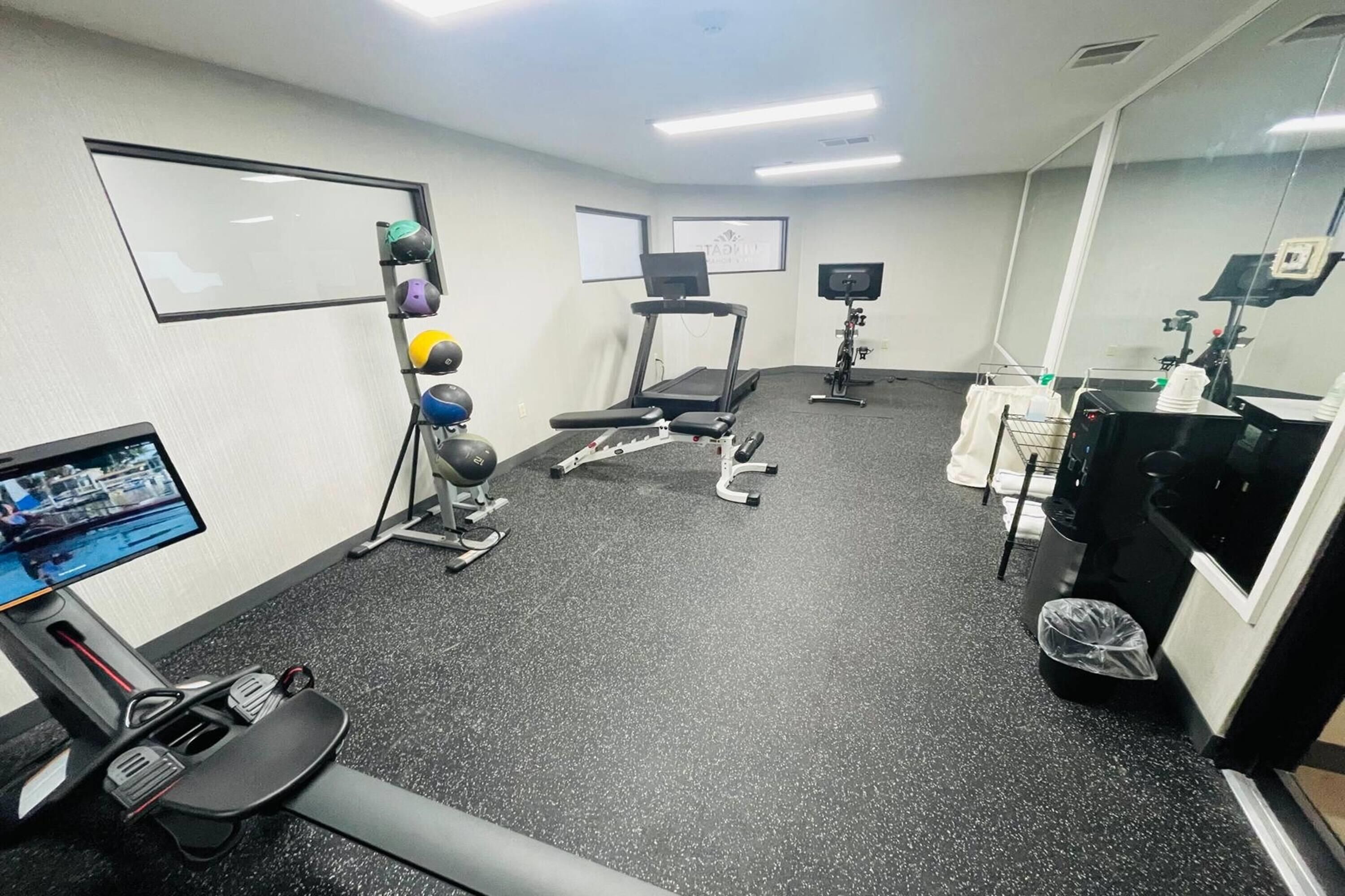 Un gimnasio con cintas de correr, pelotas de ejercicio y una bicicleta estática.