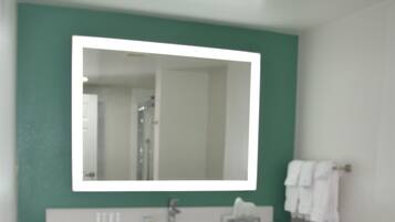 A bathroom with a white sink, mirror, and toilet.