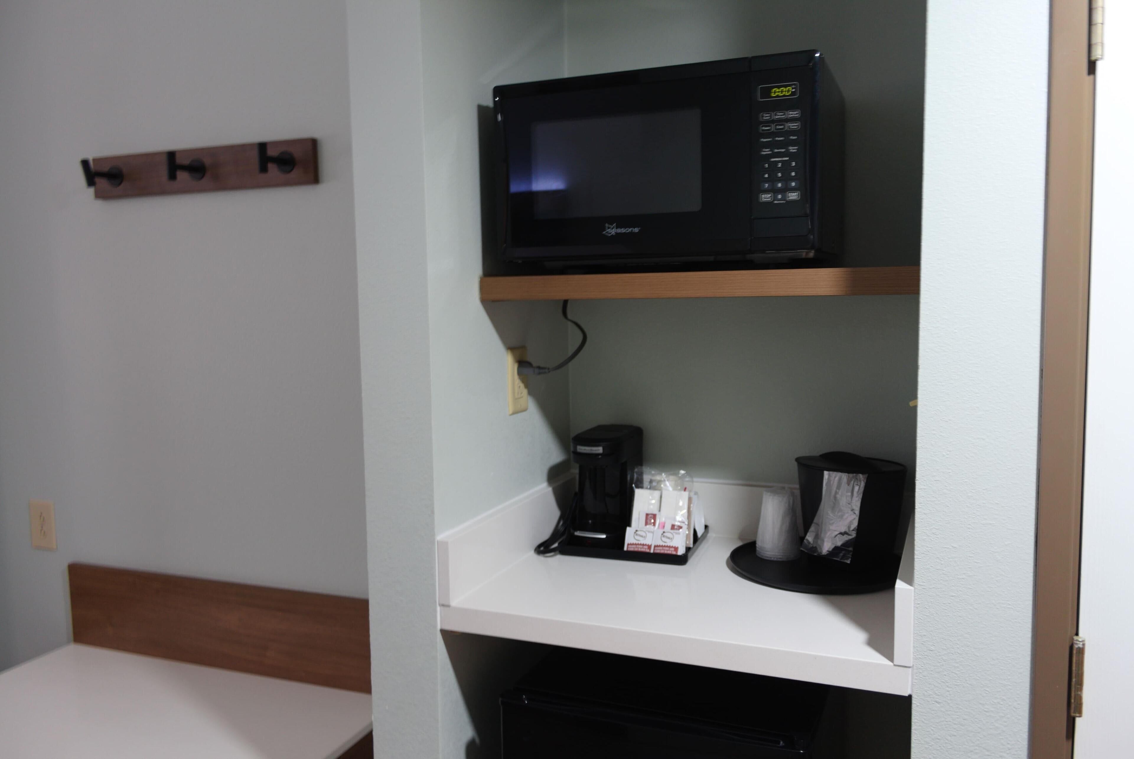 A kitchenette with a microwave, coffee maker, and a small shelf.