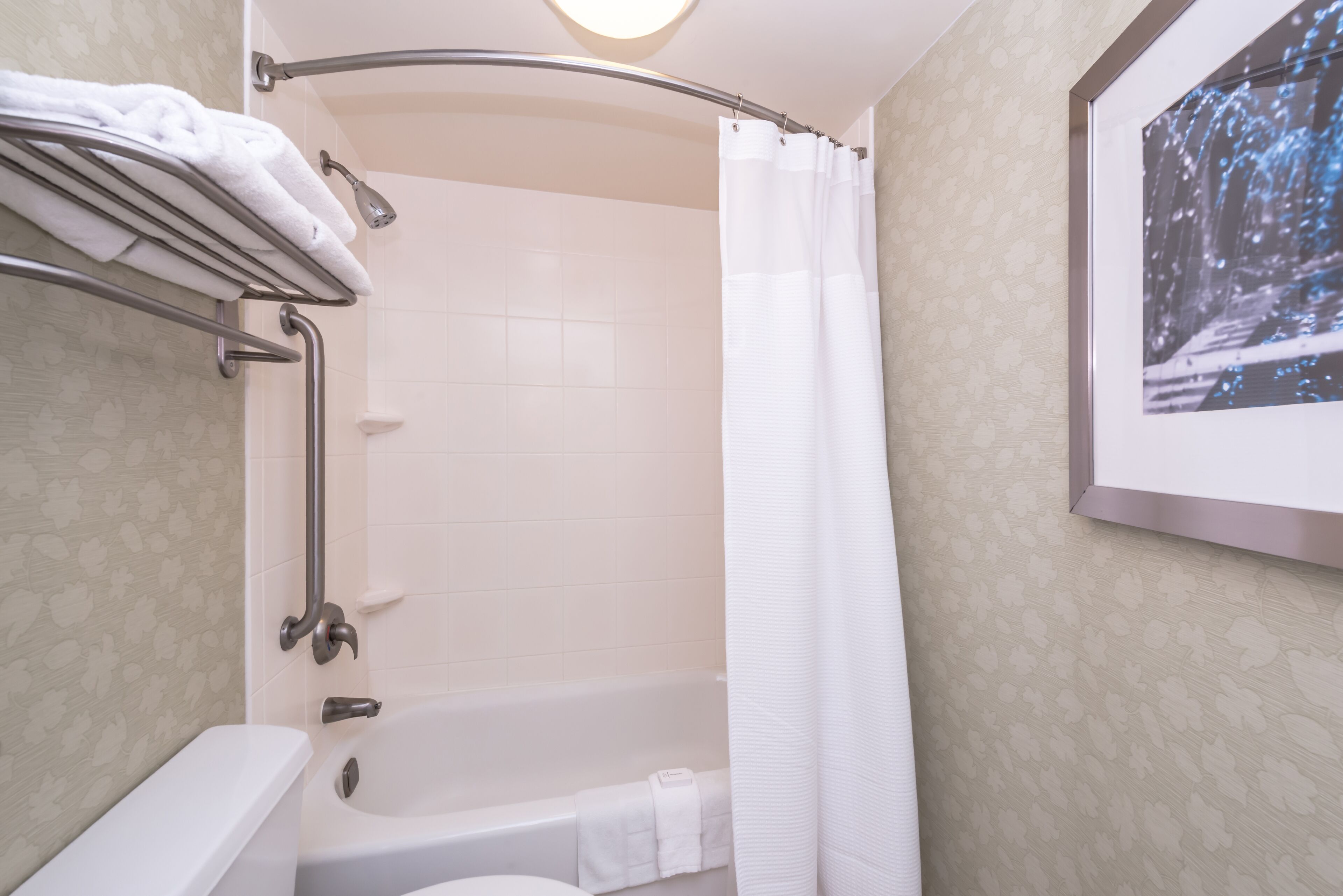 A bathroom with a bathtub, a toilet, a shower, and a towel rack.