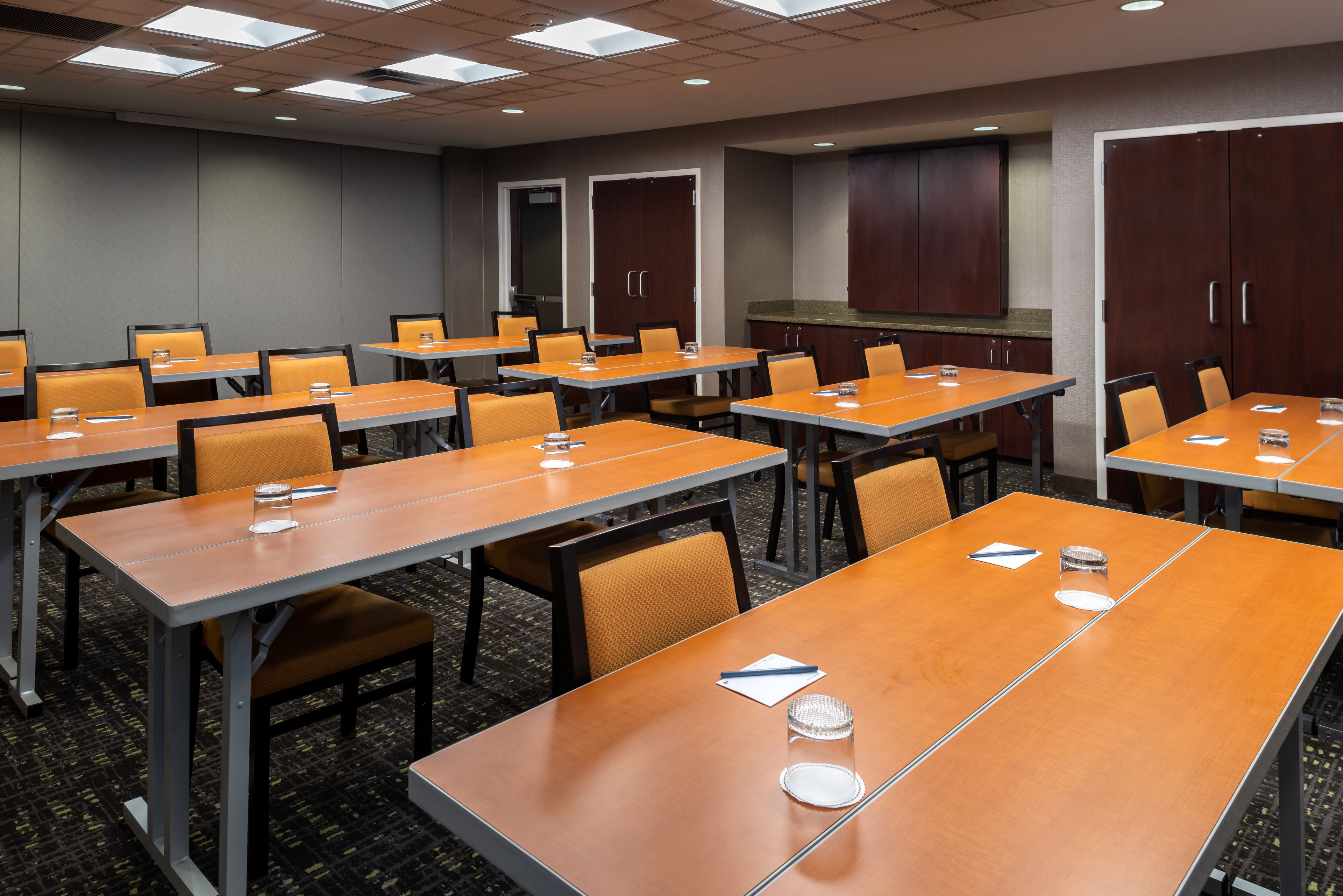A conference room with multiple tables and chairs, equipped with nameplates and water glasses.