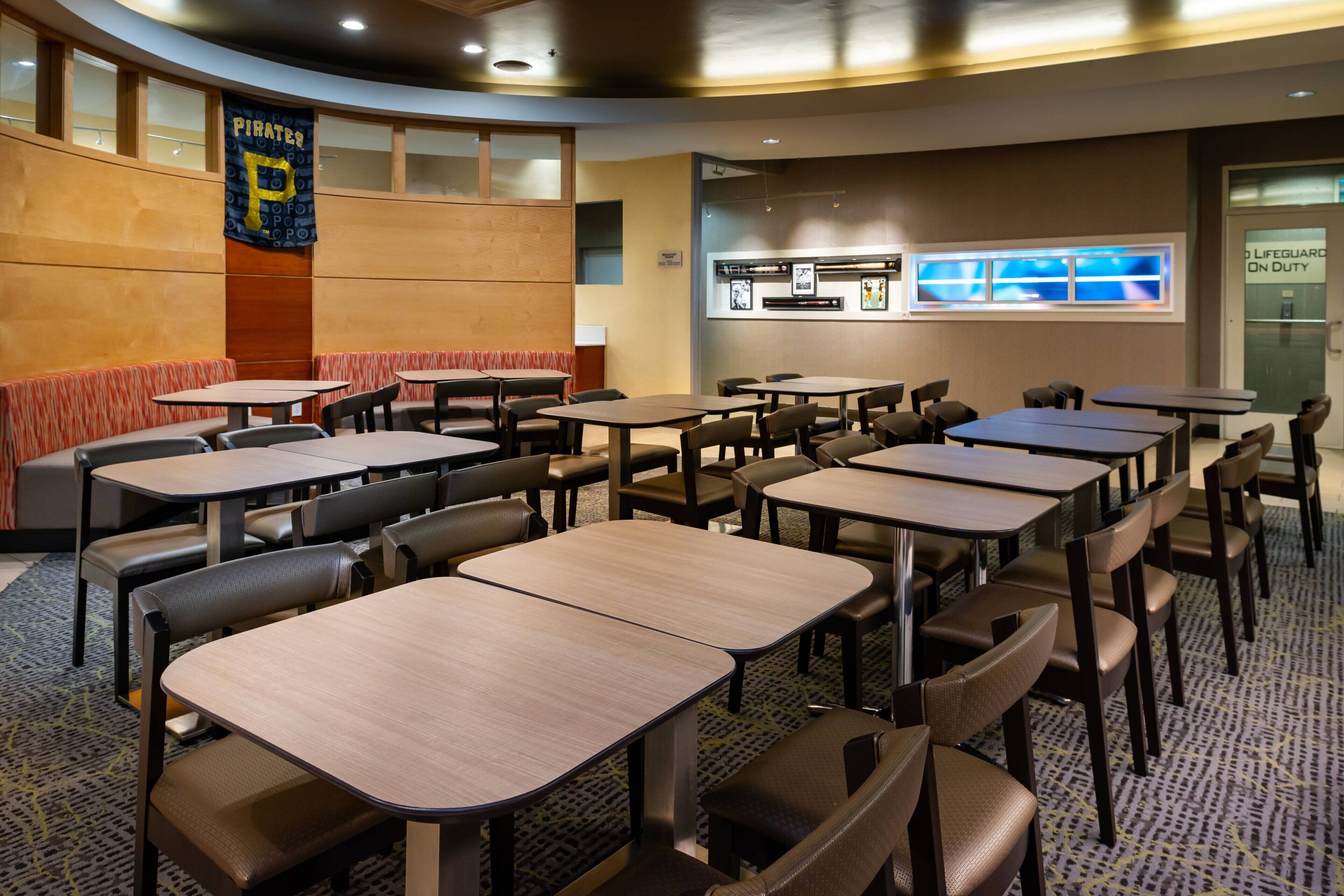 Un restaurante con cabinas y mesas, un cartel que indica la presencia de un socorrista y un banderín con la letra 'P'.