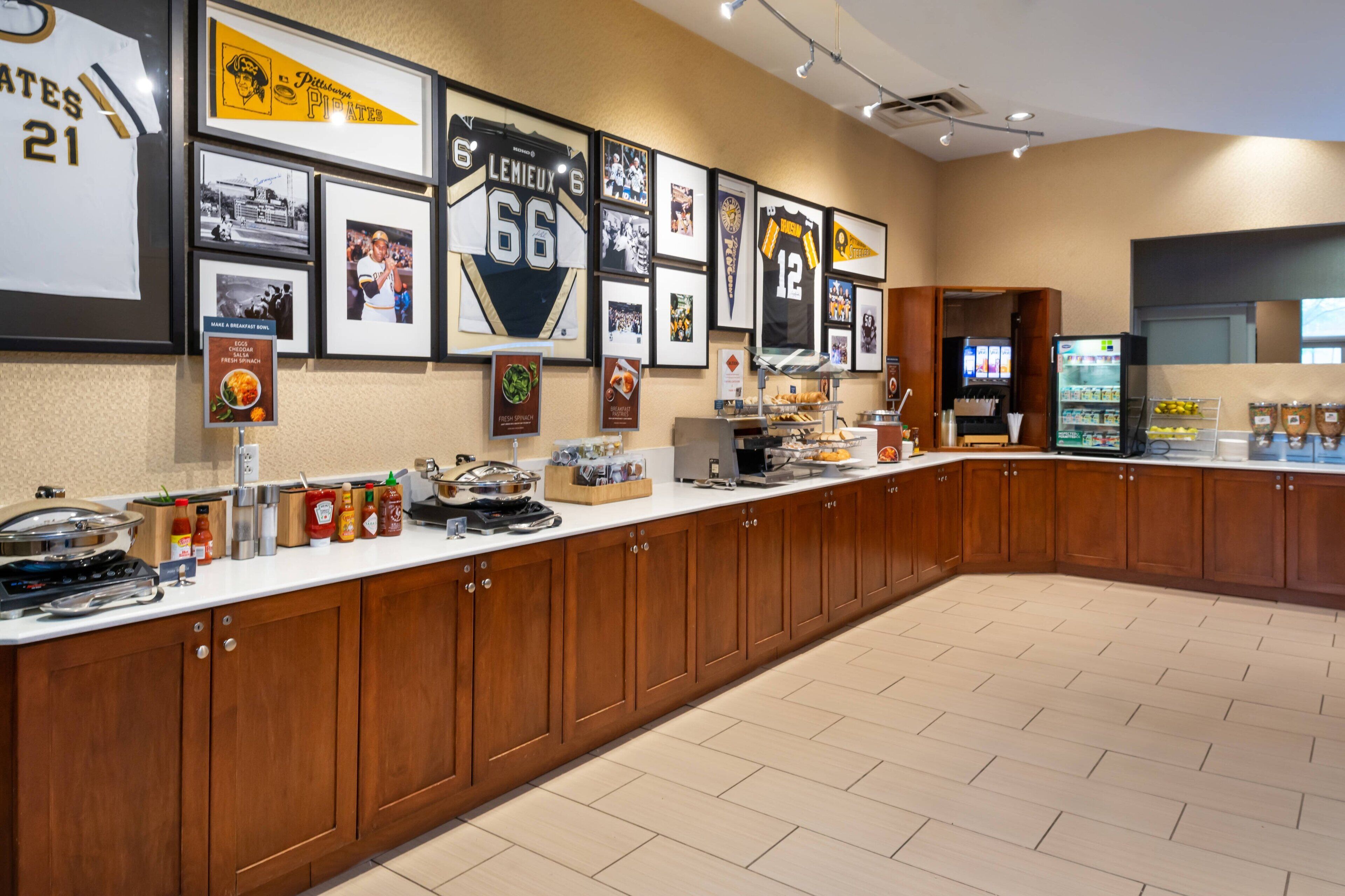 A long counter with wooden cabinets, a refrigerator, and various food items.