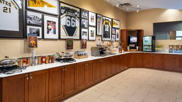 A long counter with wooden cabinets, a refrigerator, and various food items.