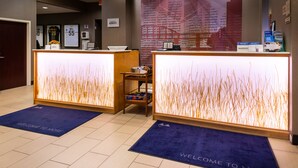 A reception area with two reception desks, a small table with a basket, and a wall with framed sports jerseys. - Springhill Suites by Marriott Pittsburgh North Shore (Pittsburgh)