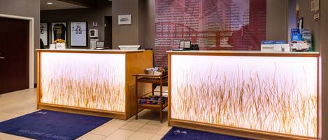 A reception area with two reception desks, a small table with a basket, and a wall with framed sports jerseys.