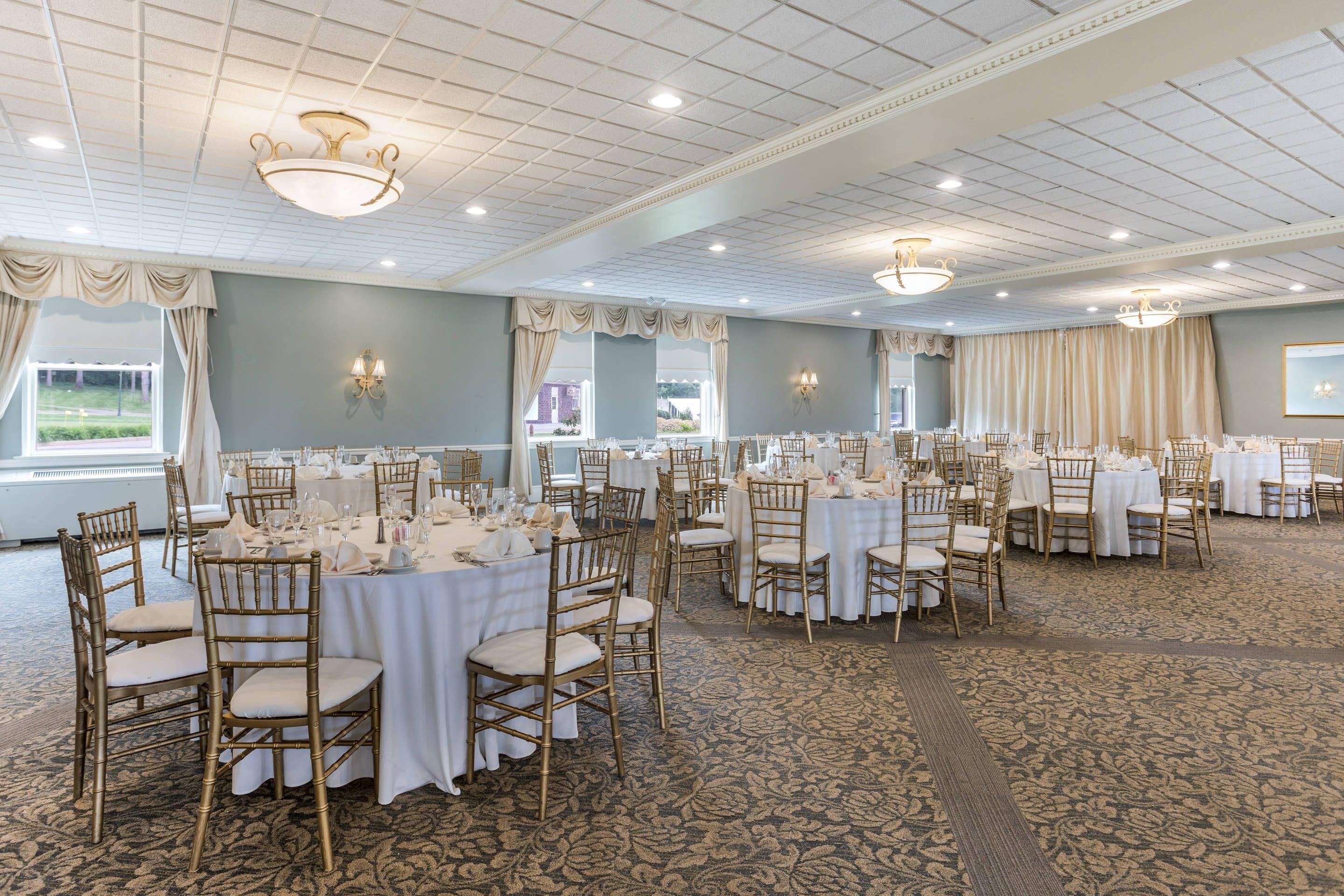 Un salón de banquetes con mesas redondas, sillas y candelabros.