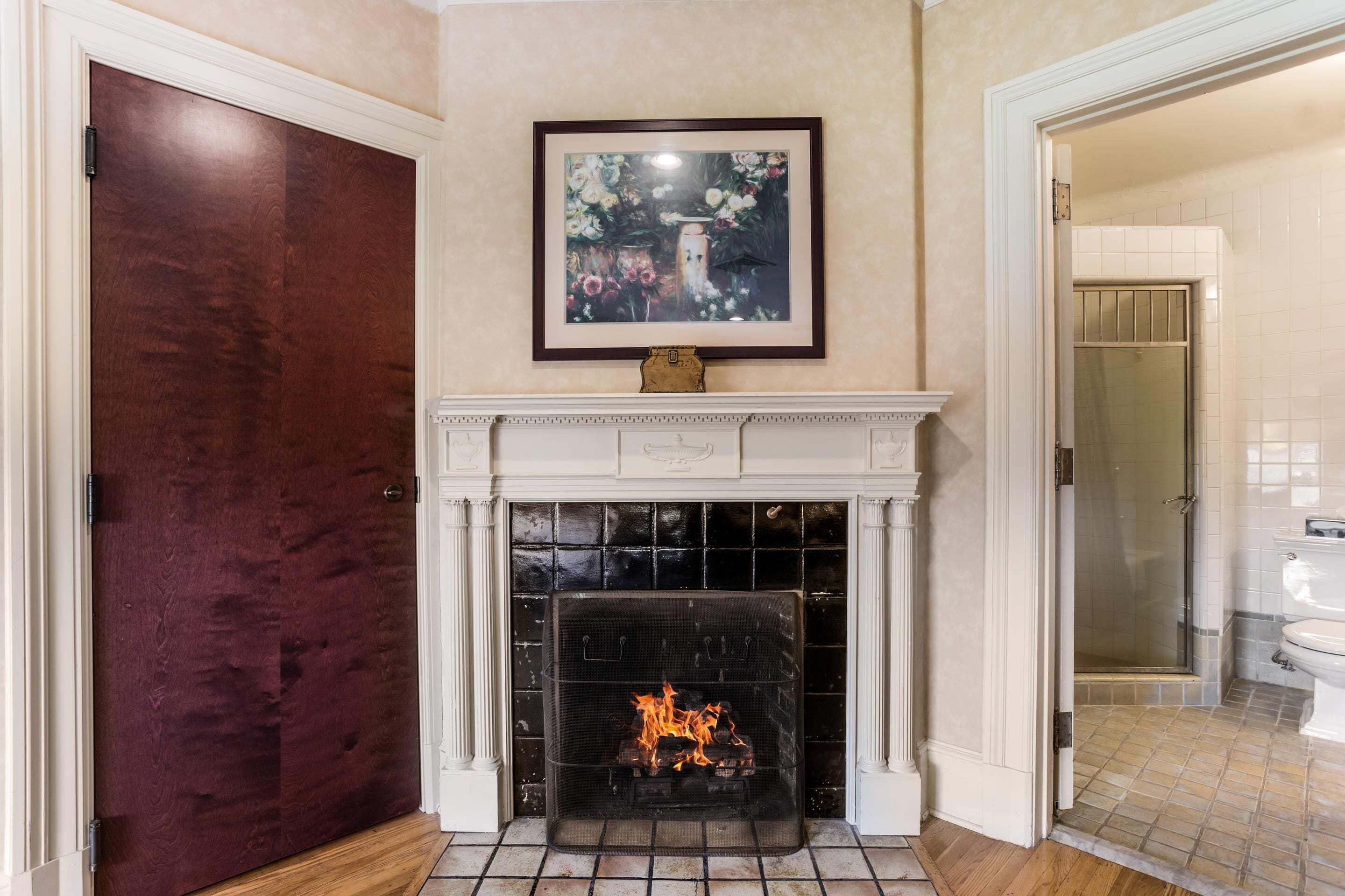 A room with a fireplace, a framed picture above it, and a door to the left.