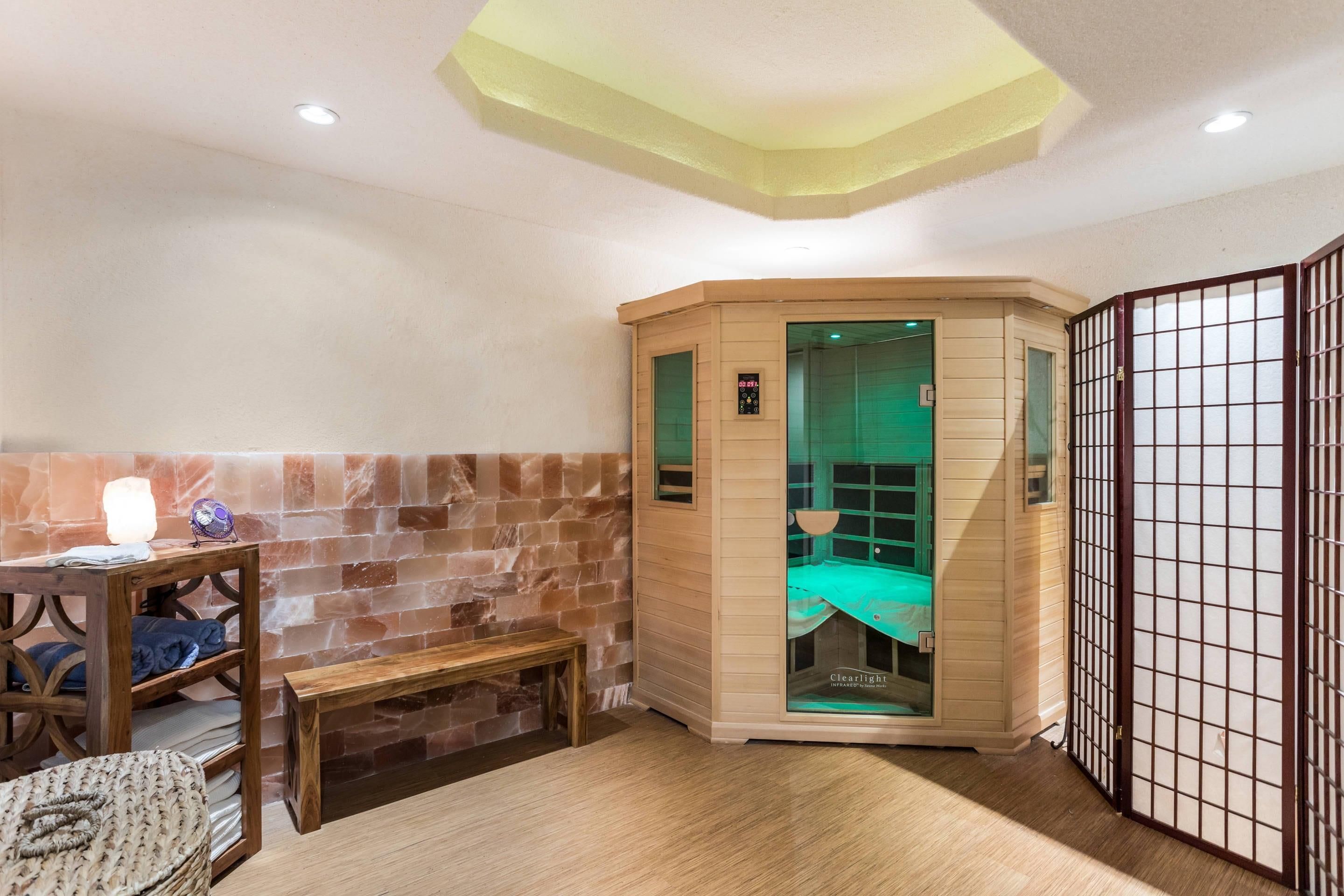 Une pièce d’angle avec un mur en pierre, un banc en bois, une table de massage et un meuble en bois.