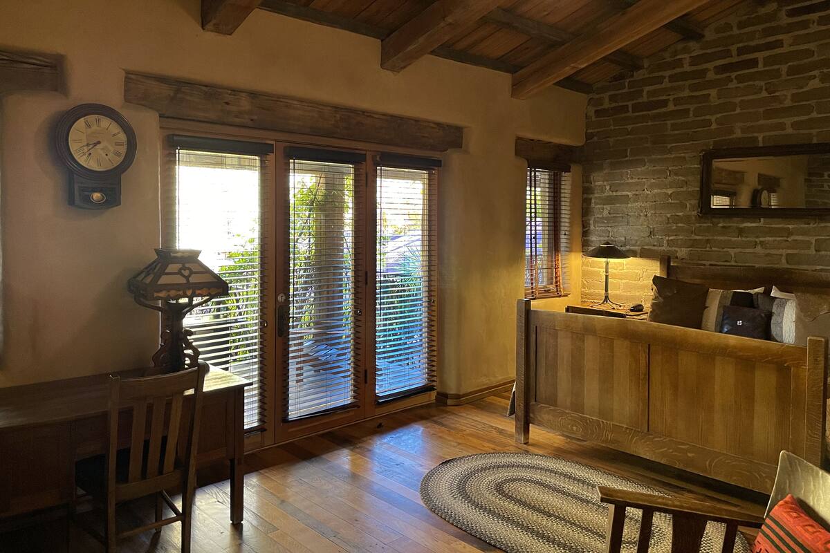 Una sala de estar acogedora con piso de madera, un sofá, una mesa de centro y una chimenea. Hay puertas de vidrio correderas que dan a un balcón con vistas a zonas verdes.