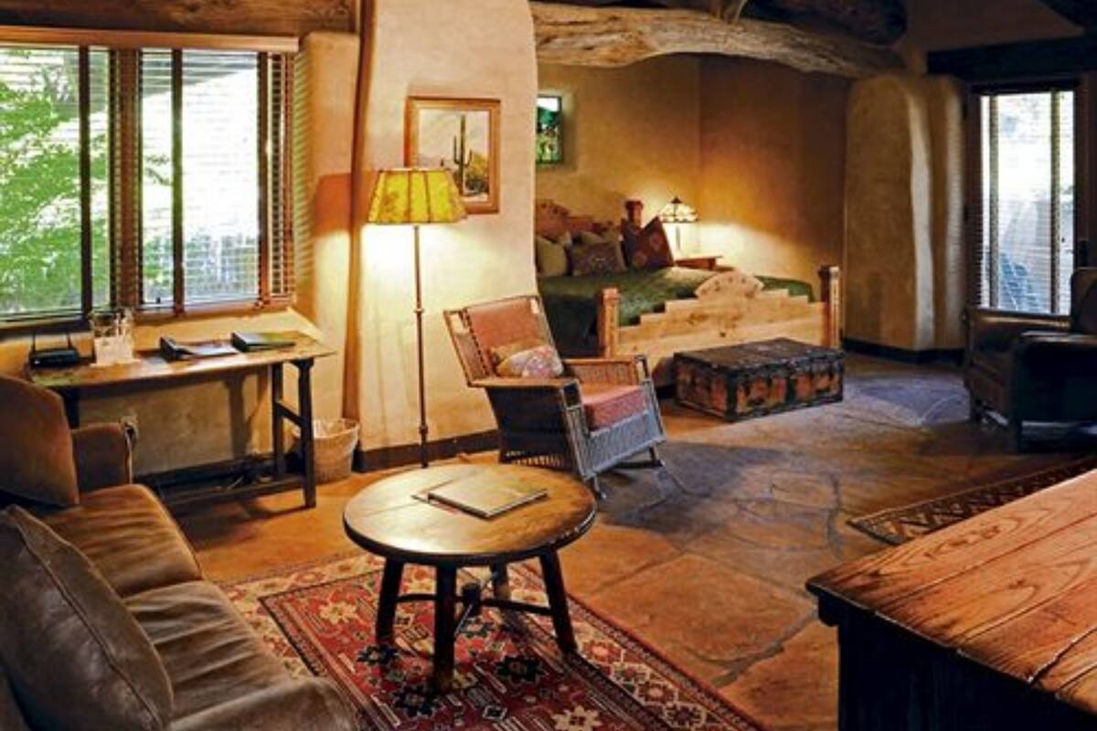 Una habitación acogedora con un escritorio de madera, un sofá cómodo, un sillón de lectura y una cama con una colcha verde.