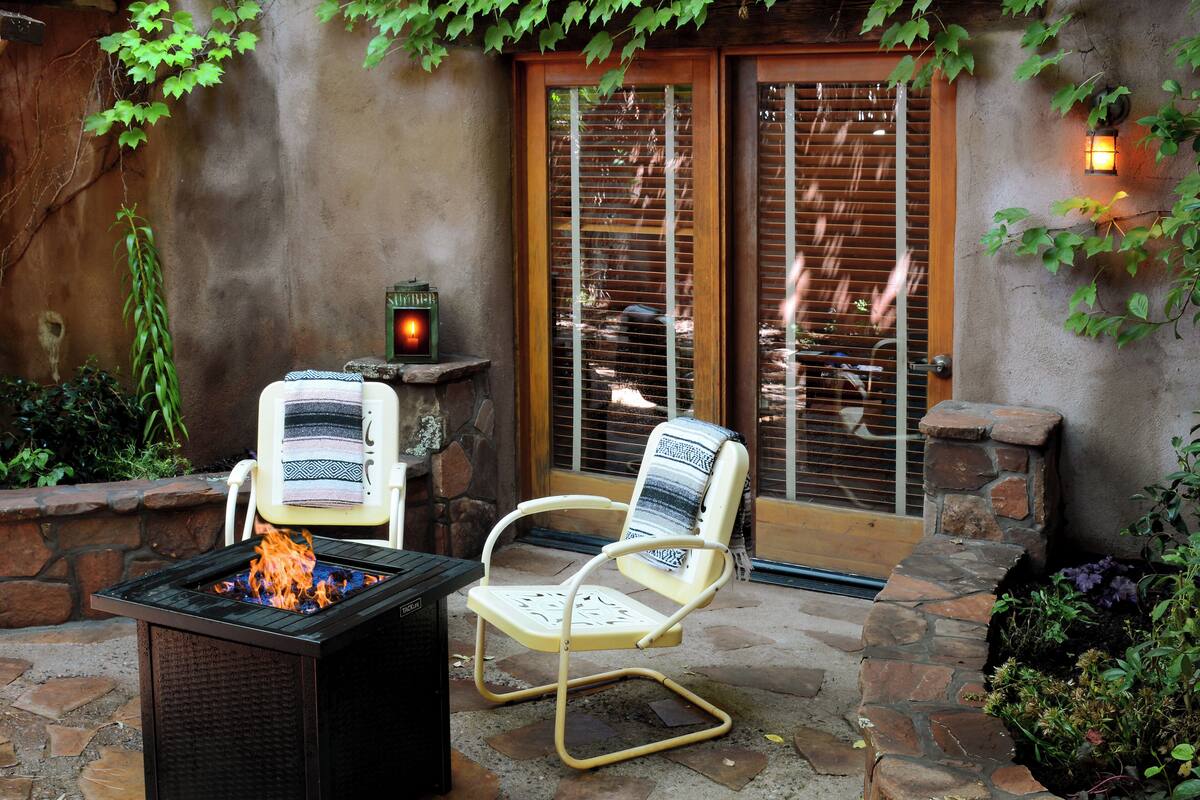 Un patio con una chimenea, dos sillas y un muro de piedra.
