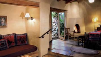 Un interior acogedor con una chimenea de piedra, una escalera de madera y un sofá rojo con cojines estampados.