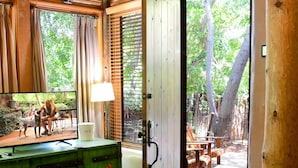 A cozy room with a wooden ceiling, a green cabinet, a wooden bench, and a view of an outdoor patio with a table and chairs.