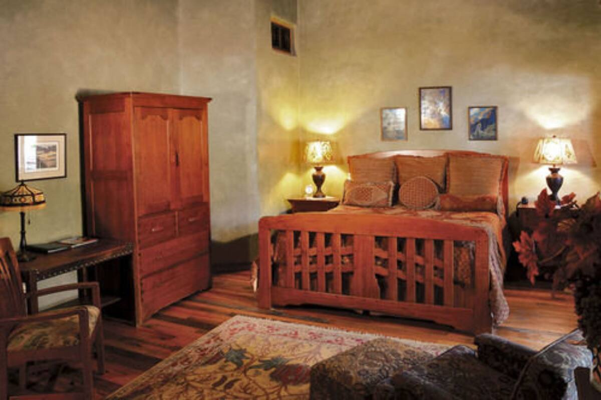 Un dormitorio acogedor con una cama de madera, una mesita de noche con lámparas, un armario de madera y un escritorio con una silla.