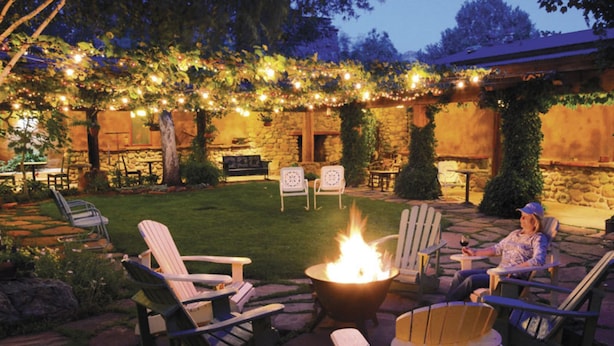 An outdoor seating area with Adirondack chairs, a fire pit, and string lights.