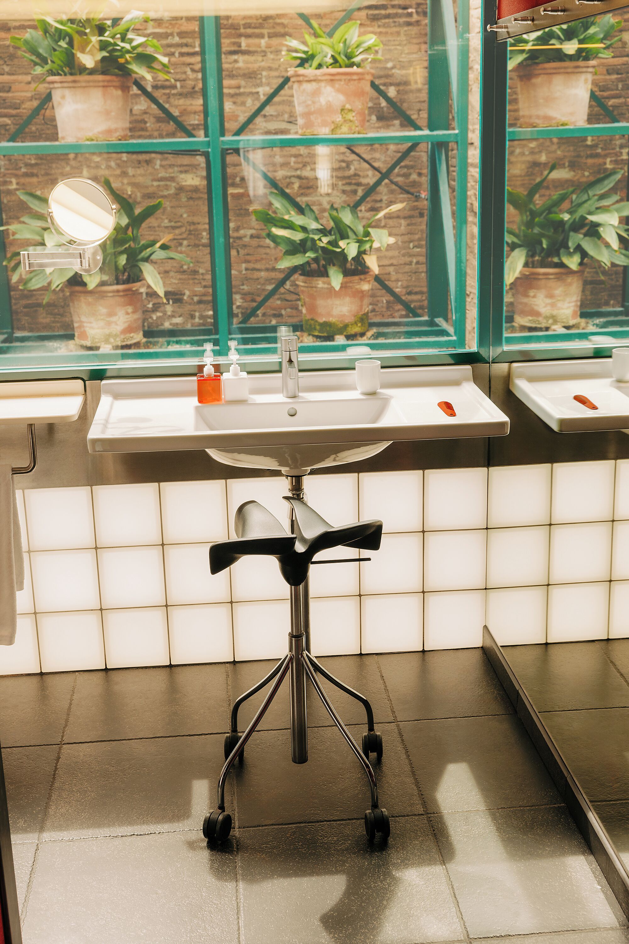 Une salle de bain avec un lavabo, un miroir et des plantes en pot près de la fenêtre.