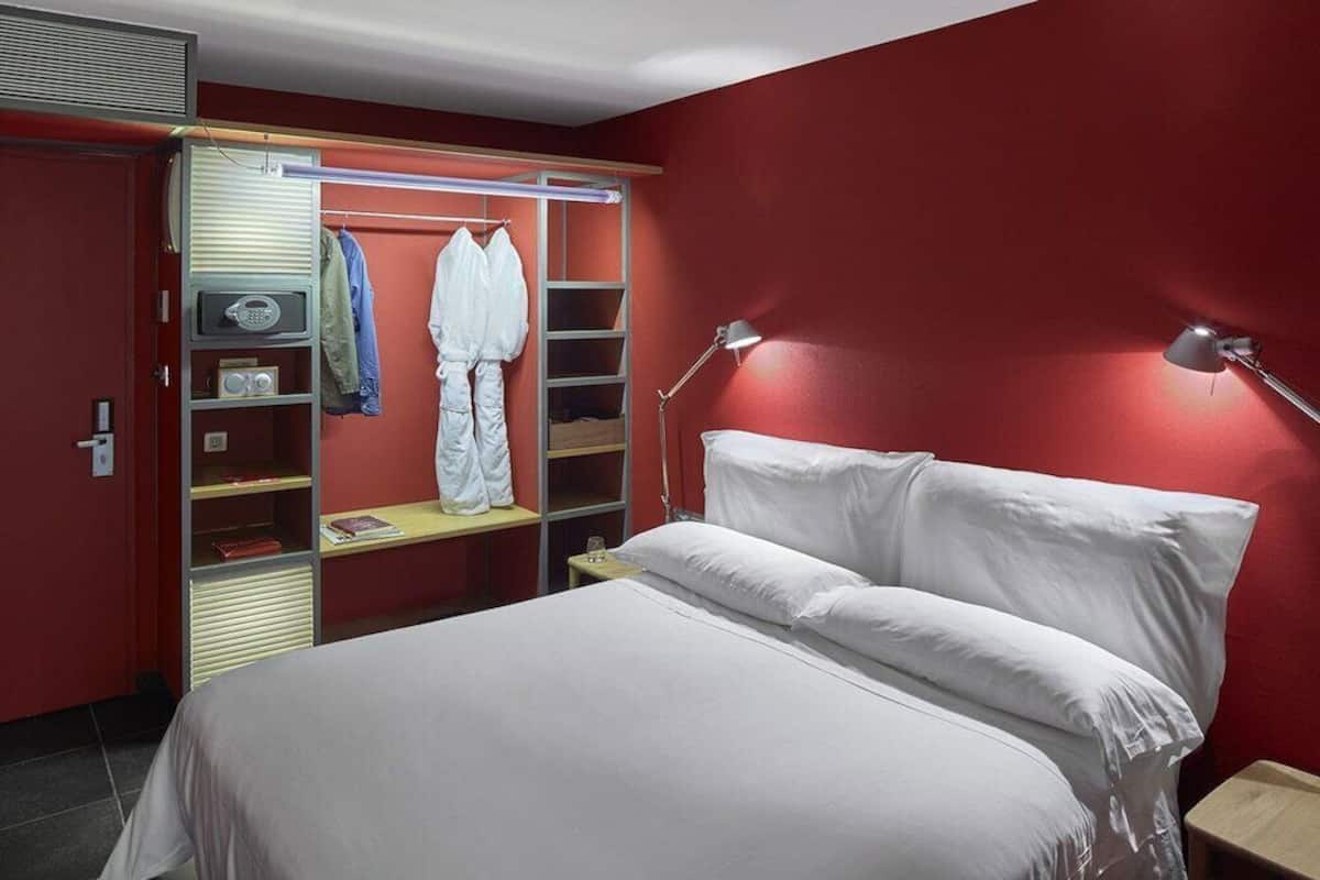 Ein Hotelzimmer mit Bett, Kleiderschrank, Schreibtisch und Lampe.