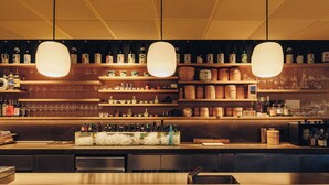 Angolo bar con scaffali pieni di bottiglie, bicchieri e arredi in legno.