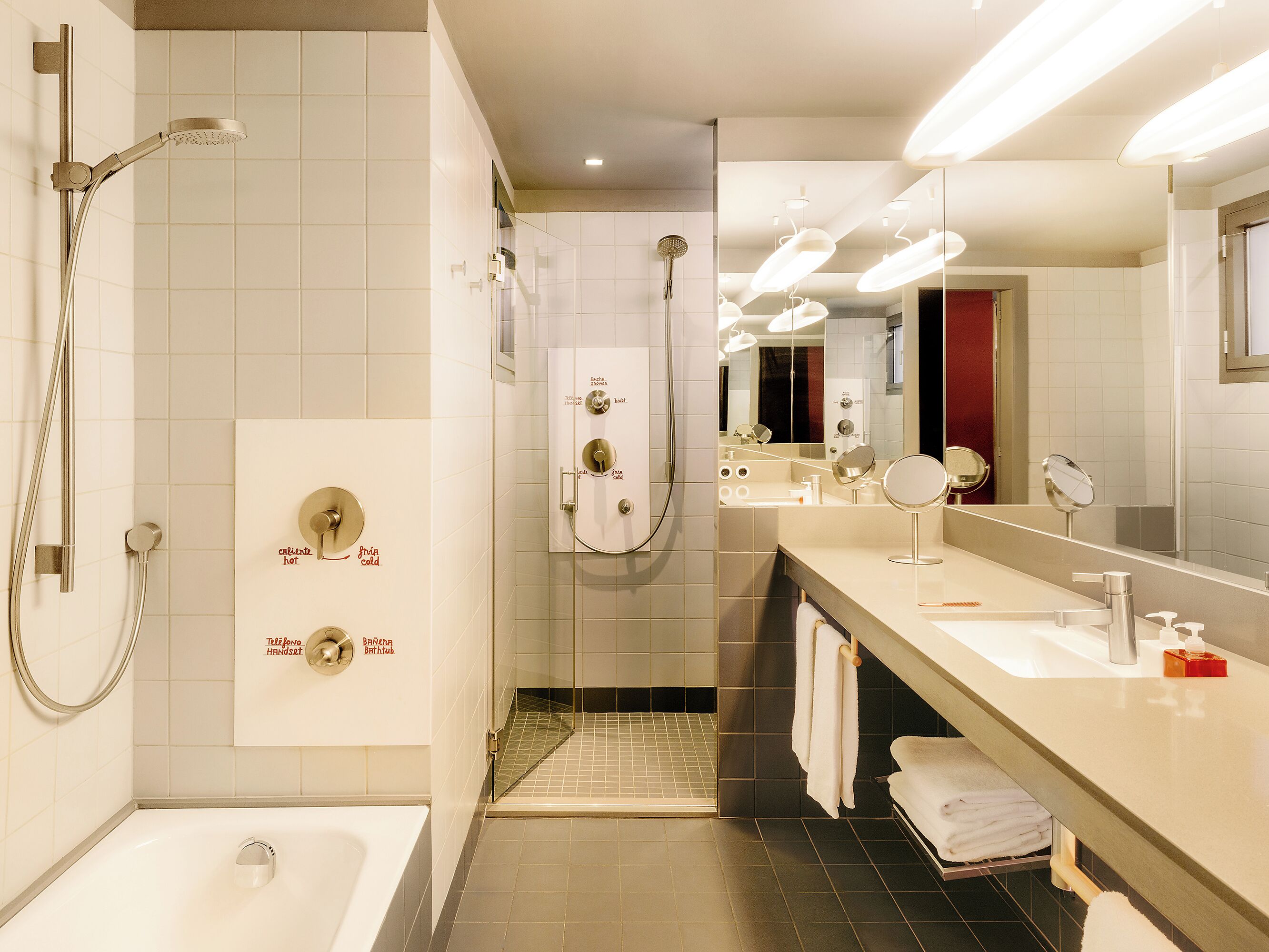 A modern bathroom with a bathtub, a shower with a handheld showerhead, a vanity with a mirror, and a towel rack.
