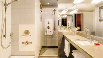 A modern bathroom with a bathtub, a shower with a handheld showerhead, a vanity with a mirror, and a towel rack.