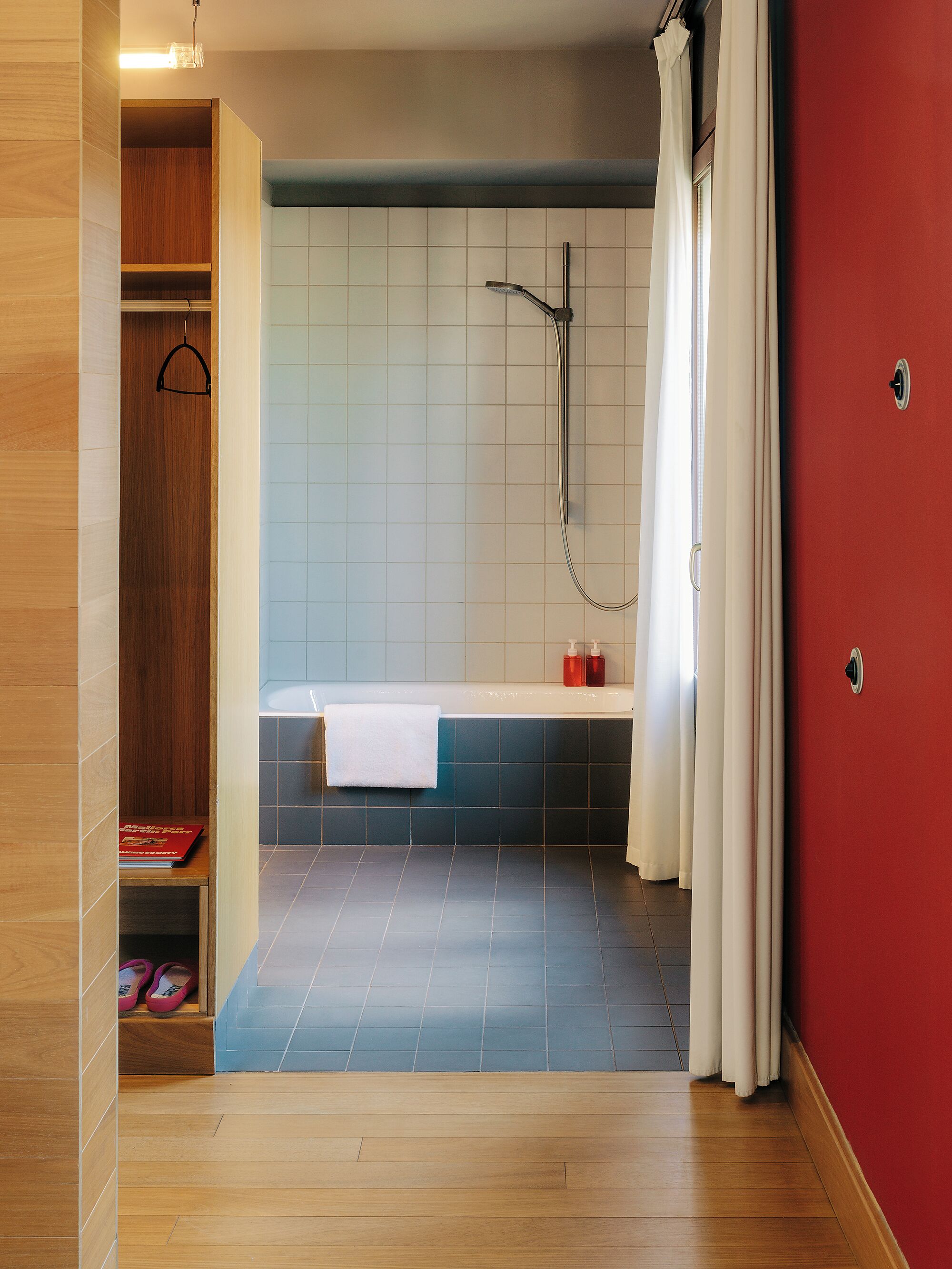 A modern bathroom with a bathtub, shower, and wooden shelving.
