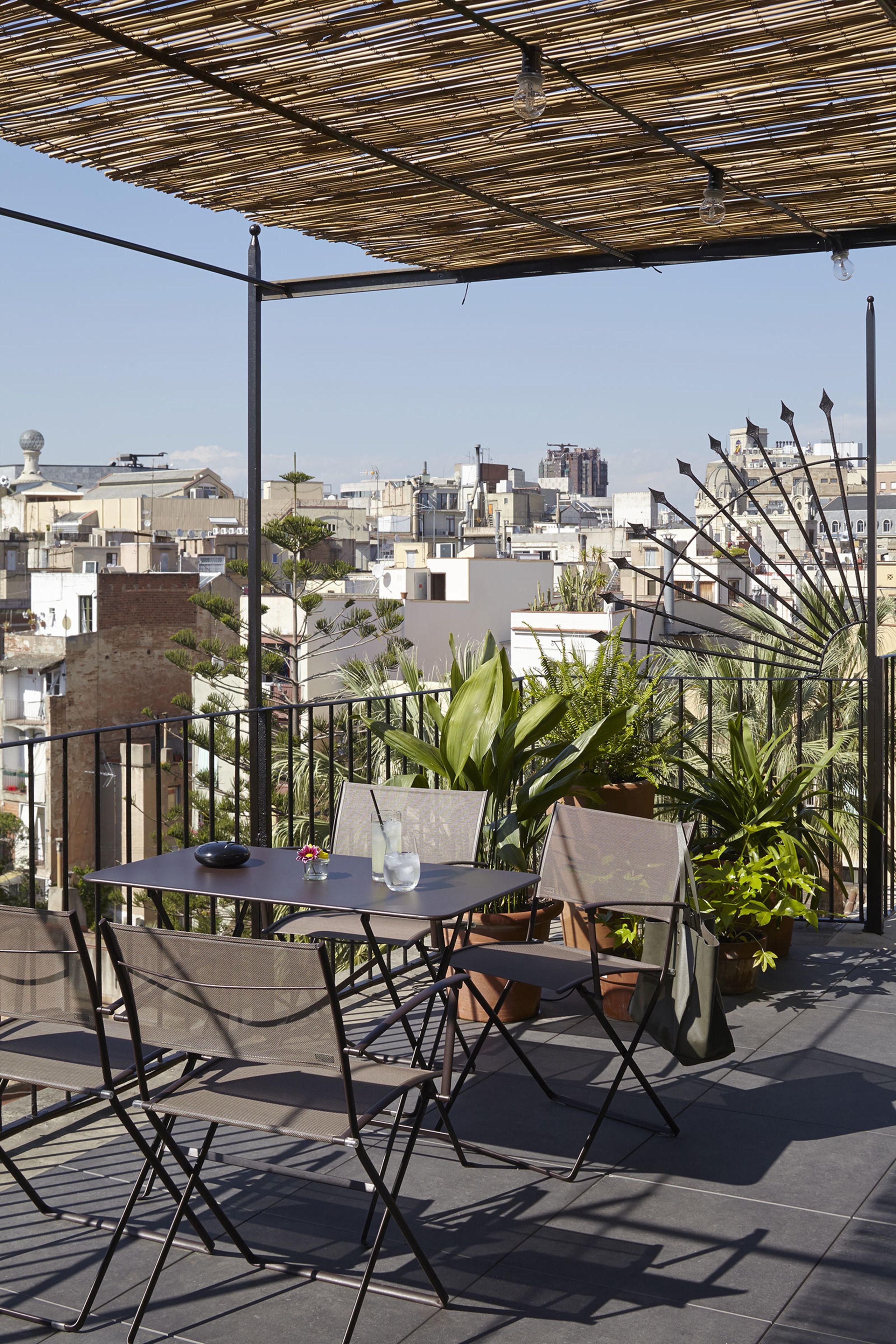 Una terrazza sul tetto con tavolo e sedie, piante in vaso e vista sulla città.