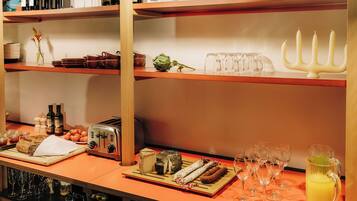 A bar area with shelves stocked with bottles, glasses, and a variety of food items.