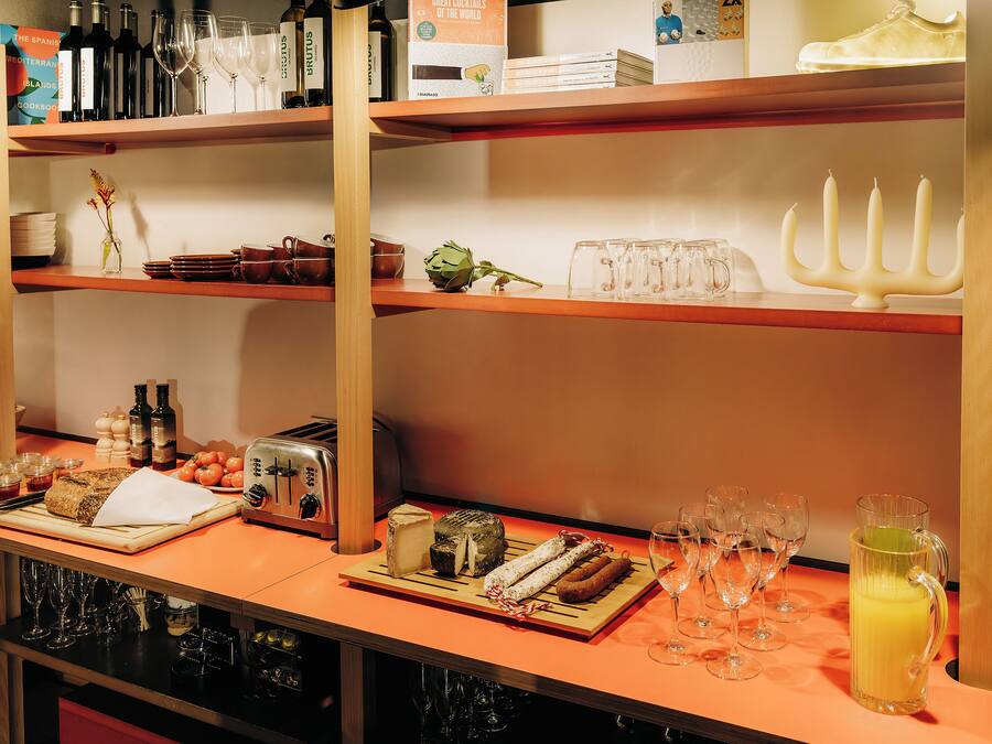 A bar area with shelves stocked with bottles, glasses, and a variety of food items.