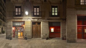 Facciata di un hotel con diversi negozi, tra cui un bar e l'hotel stesso.